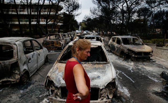 Lokalna prebivalka si v Mati ogleduje uničene avtomobile na eni izmed ulic. FOTO: Costas Baltas/Reuters