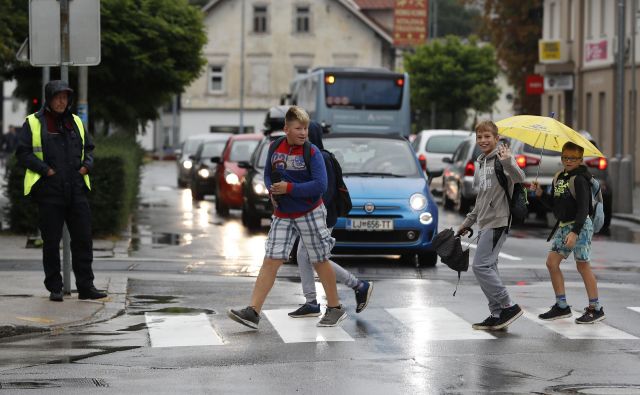 Policisti opozarjajo starše, naj otroke pred prihodom v šolo naučijo spoznati barve na semaforju in pravilno prečkati cesto. FOTO: Leon Vidic/Delo