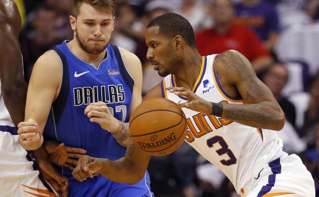 Luka Dončić (ustavlja napad Trevorja Arize) je ob debiju prispeval 10 točk. FOTO: Matt York/AP