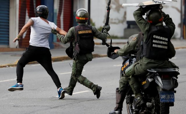 Pripadniki venezuelskih varnostnih sil lovijo protestnika med januarskimi protivladnimi demonstracijami v Caracasu, med katerimi je bilo pridržanih 740 ljudi. FOTO: Reuters