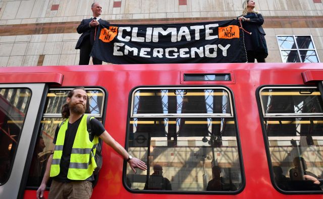 Na današnjem protestu se je moški na sliki s super lepilom prilepil na vrata stoječega vlaka. FOTO: Daniel Leal-olivas/Afp