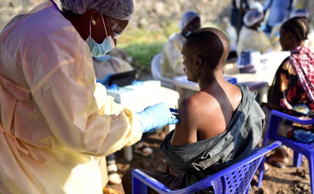 Kongovski zdravstveni delavec daje cepivo ebole moškemu v zdravstvenem centru Himbi v Gomi. FOTO: Olivia Acland/Reuters
