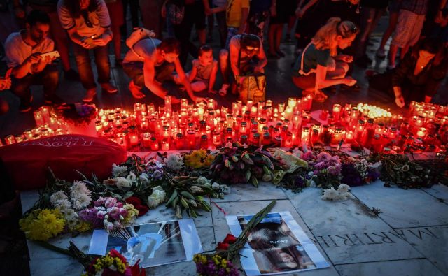 Ljudje prižigajo sveže ob spominskem obeležju pred notranjim ministrstvom. FOTO: Daniel Mihailescu/AFP