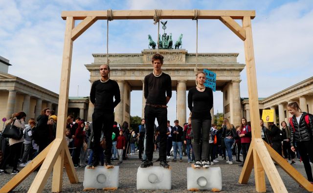 Aktivisti pred Brandenburškimi vrati opozarjajo na segrevanje planeta. FOTO: Fabrizio Bensch/Reuters