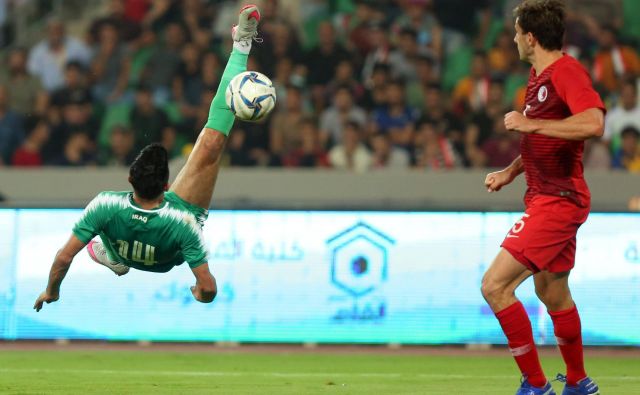 Iračan Amjad Attwan je z atraktivnim poskusom želel zabiti gol. Ni bil uspešen, a je Irak vseeno dosegel prvo kvalifikacijsko zmago pred domačimi navijači v Basri. FOTO: AFP