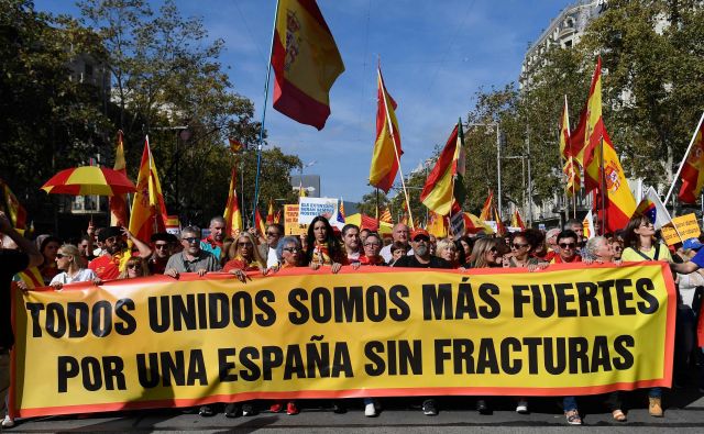 Ljudje ob transparentu z napisom »Skupaj smo močnejši, za Španijo brez zlomov«. FOTO: Josep Lago/AFP