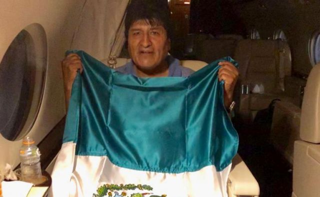 Evo Morales z mehiško zastavo na letalu, ki ga je zanj v La Paz poslala Mehika. FOTO: Reuters