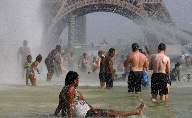 Hlajenje ob Eiffelovmu stolpu julija lani, ko je Pariz zajel nov rekorden vročinski val. FOTO: Pascal Rossignol/Reuters