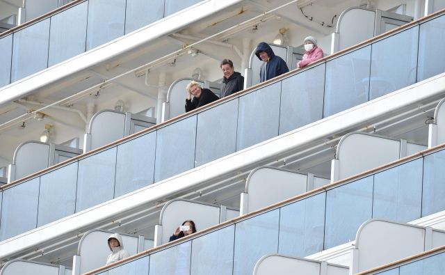 Potniki na krovu križarke Diamond Princess ob prihodu v pristanišče Jokohama. FOTO: Kazuhiro Nogi/AFP