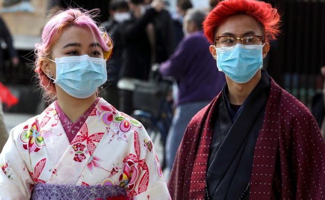 Turisti z maskami v japonski prestolnici. FOTO: Athit Perawongmetha/Reuters