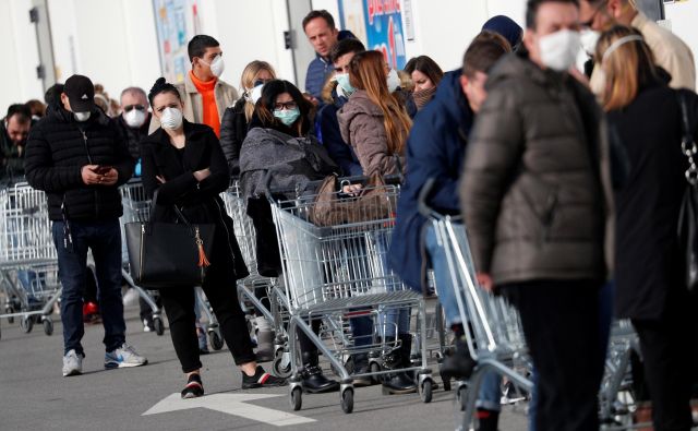 V mesto Casalpusterlengo v severni Italiji, ki je zaradi izbruha virusa zaprto v karenteno, ljudje v vrstah stojijo pred trgovinami z živili. FOTO: Guglielmo Mangiapane/Reuters