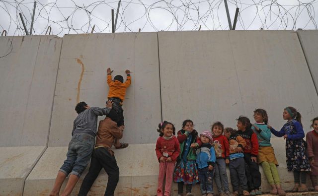 Otroški begunci, ujeti na severu Sirije, poskušajo preplezati zid, ki ga je Turčija postavila na meji, da bi preprečila prihod beguncev iz Sirije. FOTO: Aaref Watad/AFP