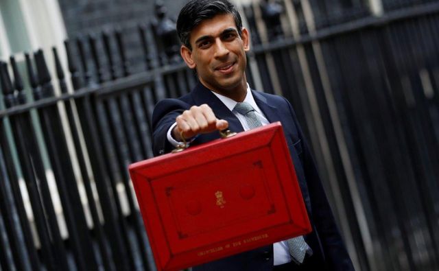 Rishi Sunak 11. decembra pred svojo pisarno na Downing Streetu s proračunskimi dokumenti v tradicionalni rdeči »proračunski škatli«. Foto Reuters