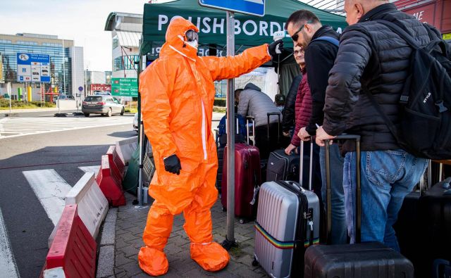 Strožji režim je na notranjih in zunanjih schengenskih mejah. Na fotografiji poljski zdravstveni delavec meri telesno temperaturo potnikom na meji z Nemčijo. FOTO: Odd Andersen/AFP