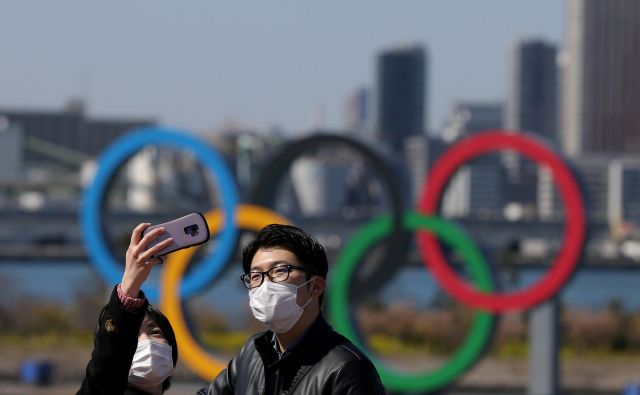 Japonci se slikajo s petimi olimpijskimi krogi z zaščitnimi maskami. FOTO: Reuters