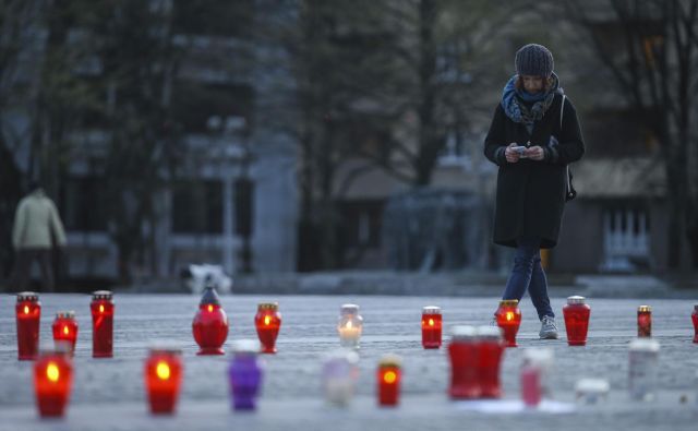 Pozno popoldan so na Trgu republike pred stavbo parlamenta zagorele sveče, ki so jih posamezniki prižigali v znak neodobravanja potez vlade. FOTO: Jože Suhadolnik/Delo