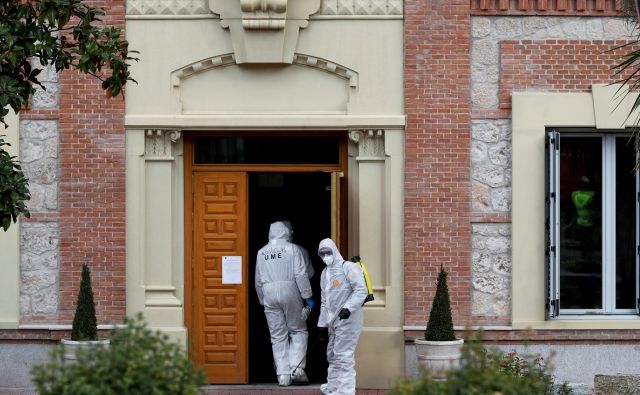 Pripadniki španske vojaške enote nujne pomoči prihajajo razkuževat enega od domov za starejše v Madridu. V nekaterih domovih so našli zapuščene in tudi že mrtve varovance. FOTO: Susana Vera/Reuters