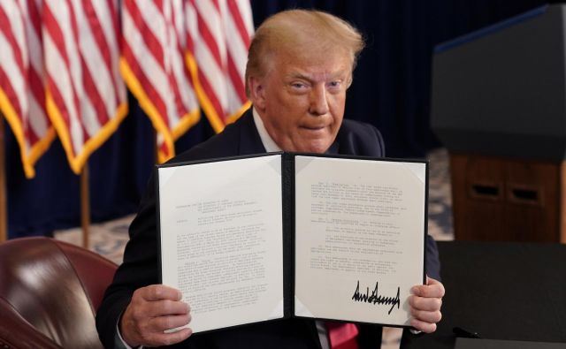 Donald Trump razkazuje svoj podpis pod izvršilnim zakonom. Foto Joshua Roberts Reuters