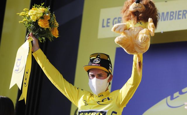 Primož Roglič drži v rokah rumeno majico vodilnega na dirki po Franciji. FOTO: Thibault Camus/Reuters