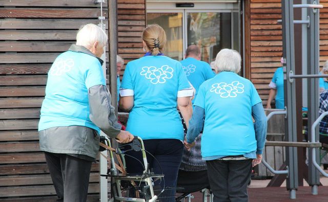 Stanovalci Doma starejših občanov Kočevje z roko v roki na sprehodu, ki ozavešča o problemu demence v Sloveniji. FOTO: Simona Fajfar/Delo