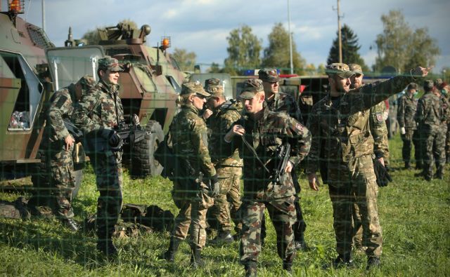 Prihod vojaških vozil in vojske pred namestitveni center, ki je v nekdanji hali podjetja Beti na Dobovi, Slovenija 20.oktobra 2015.
[Dobova,Slovenija,begunci,Slovenska vojska,orožje,puške,vojaška vozila,emigranti,moški,očetje,otroci,begunski